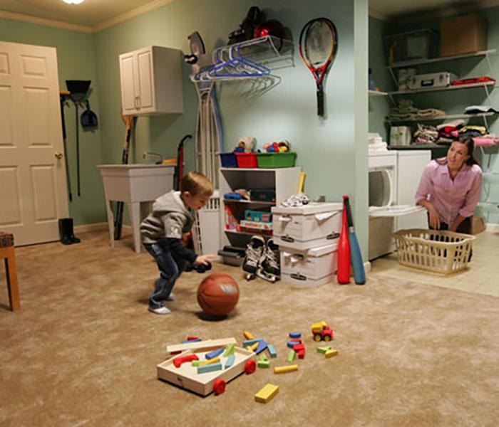 small child dribbling a basketball, mom looking on from the washing machine area