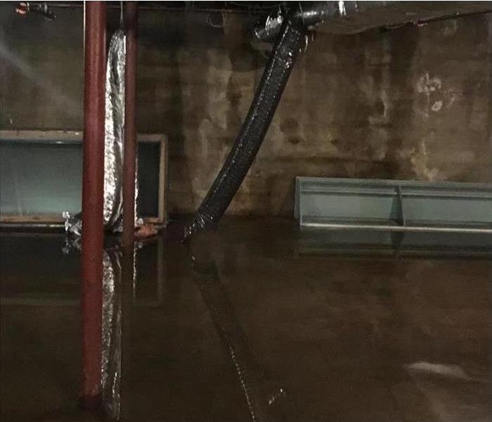 dark basement, unfinished, with concrete walls and pad, several inches of standing water