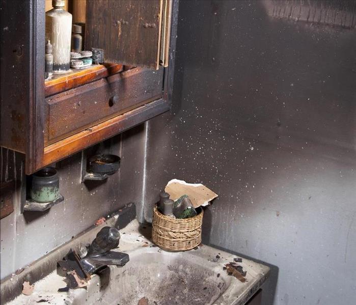 A bathroom sink with fire and soot damage. 