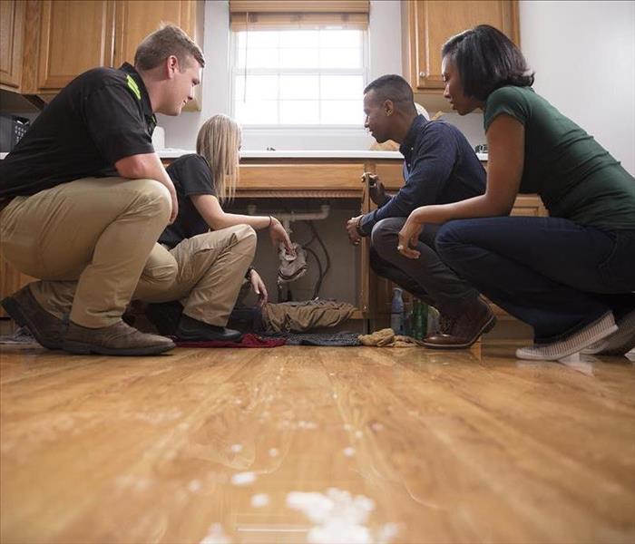SERVPRO techs and homeowners look over water damage to a home.