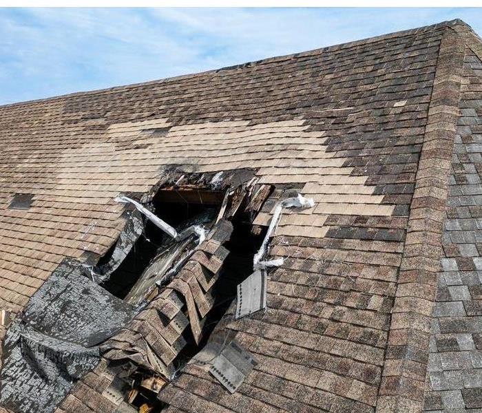 Roof with a huge hole that was damaged during a storm